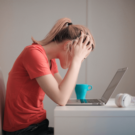 Woman holding her head while working at a desk